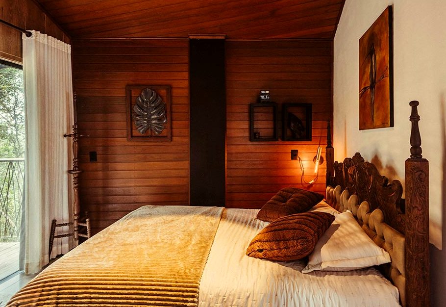 A carved timber bedhead against a panelled wall, lamps lit on both sides