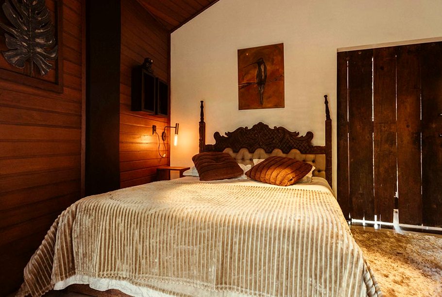 A long room with a pale ceiling, tall dark doors and a gold bedcover