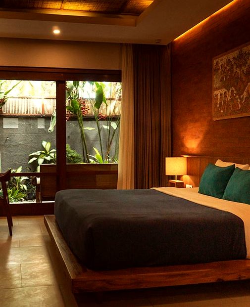 A room with dark timber walls, a low bed and garden doors standing open
